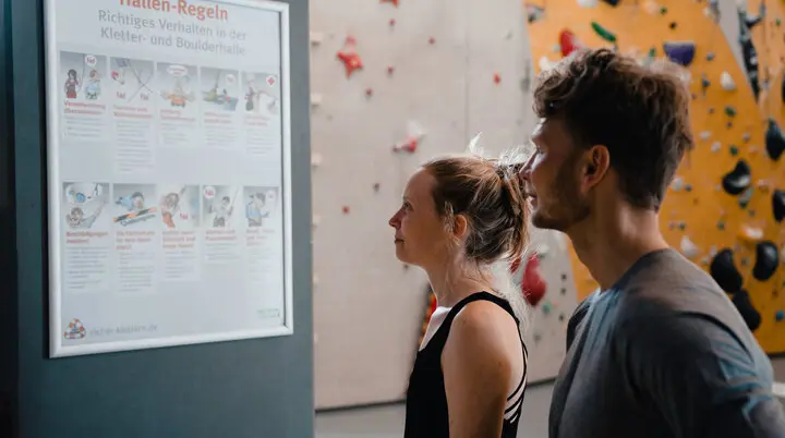 Zwei Personen checken den Trainingsplan, der an einer Wand hängt | © DAV/Marisa Koch